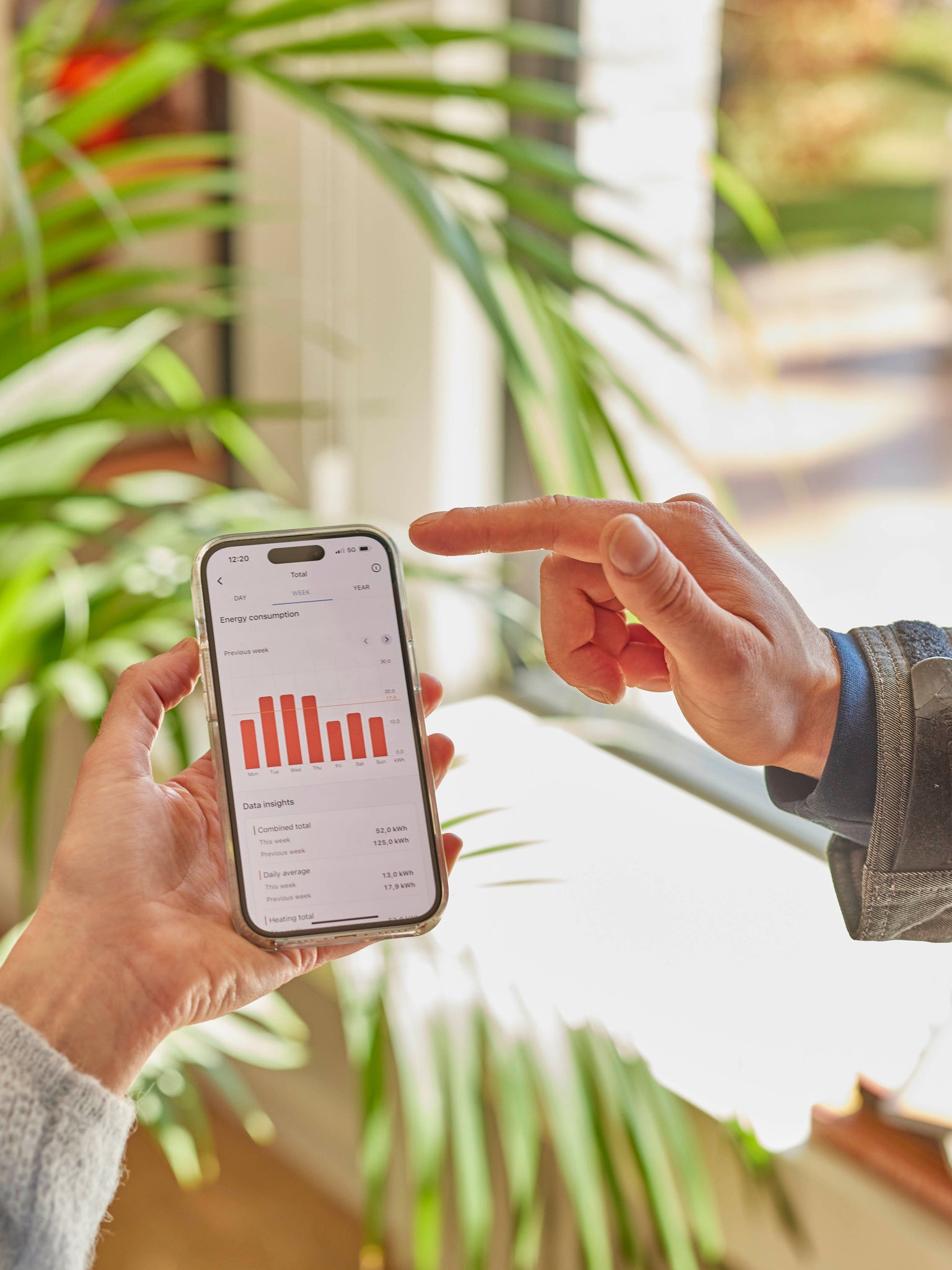 Två personer som tillsammans granskar prestandadata för en värmepump i en mobilapp
