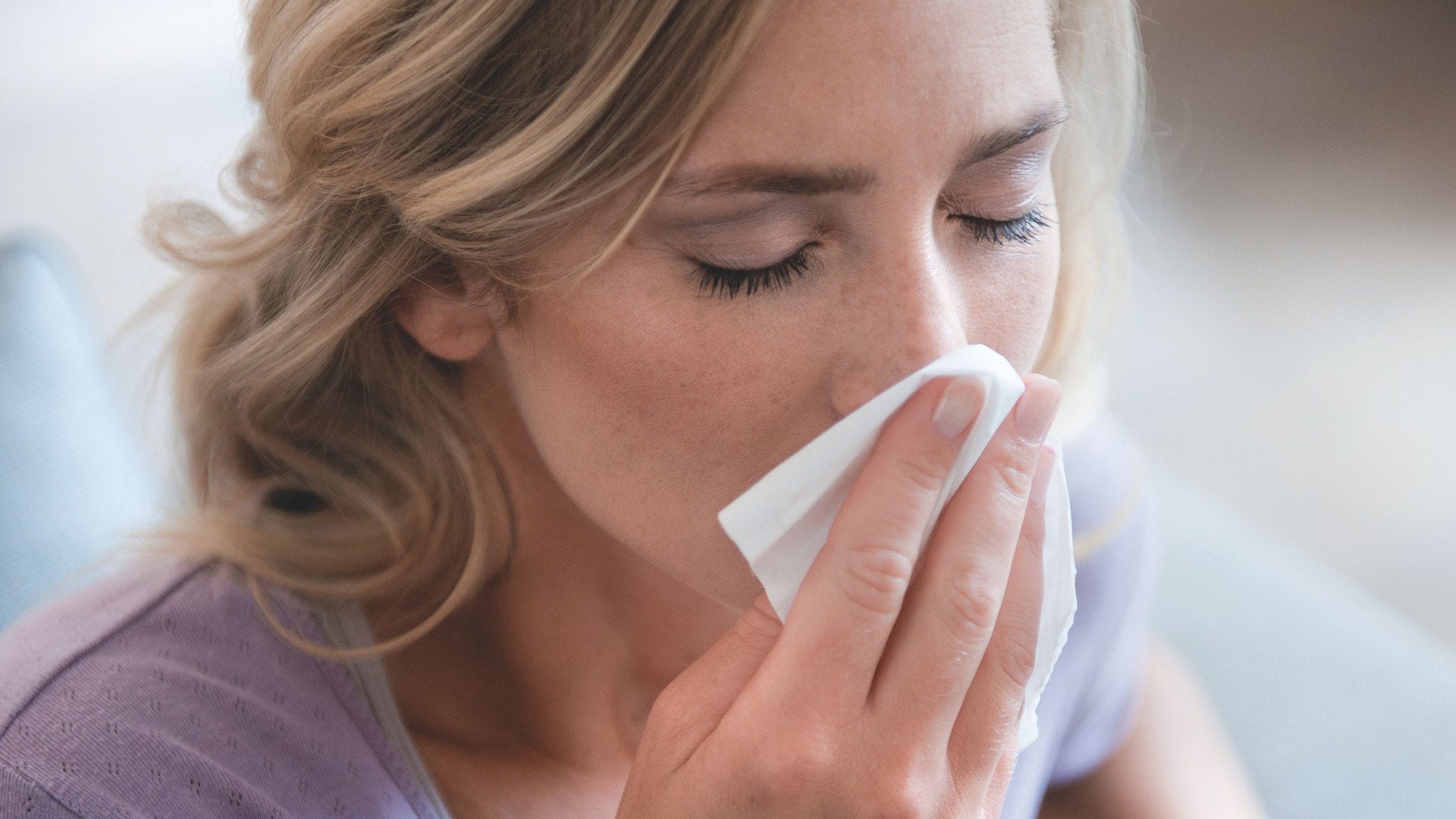 En kvinna som snyter sig på grund av pollenallergi