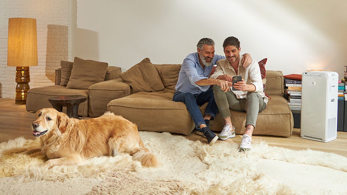 Far och son tittar i en mobiltlefon och njuter av ren luft tack vare en Daikin luftrenare