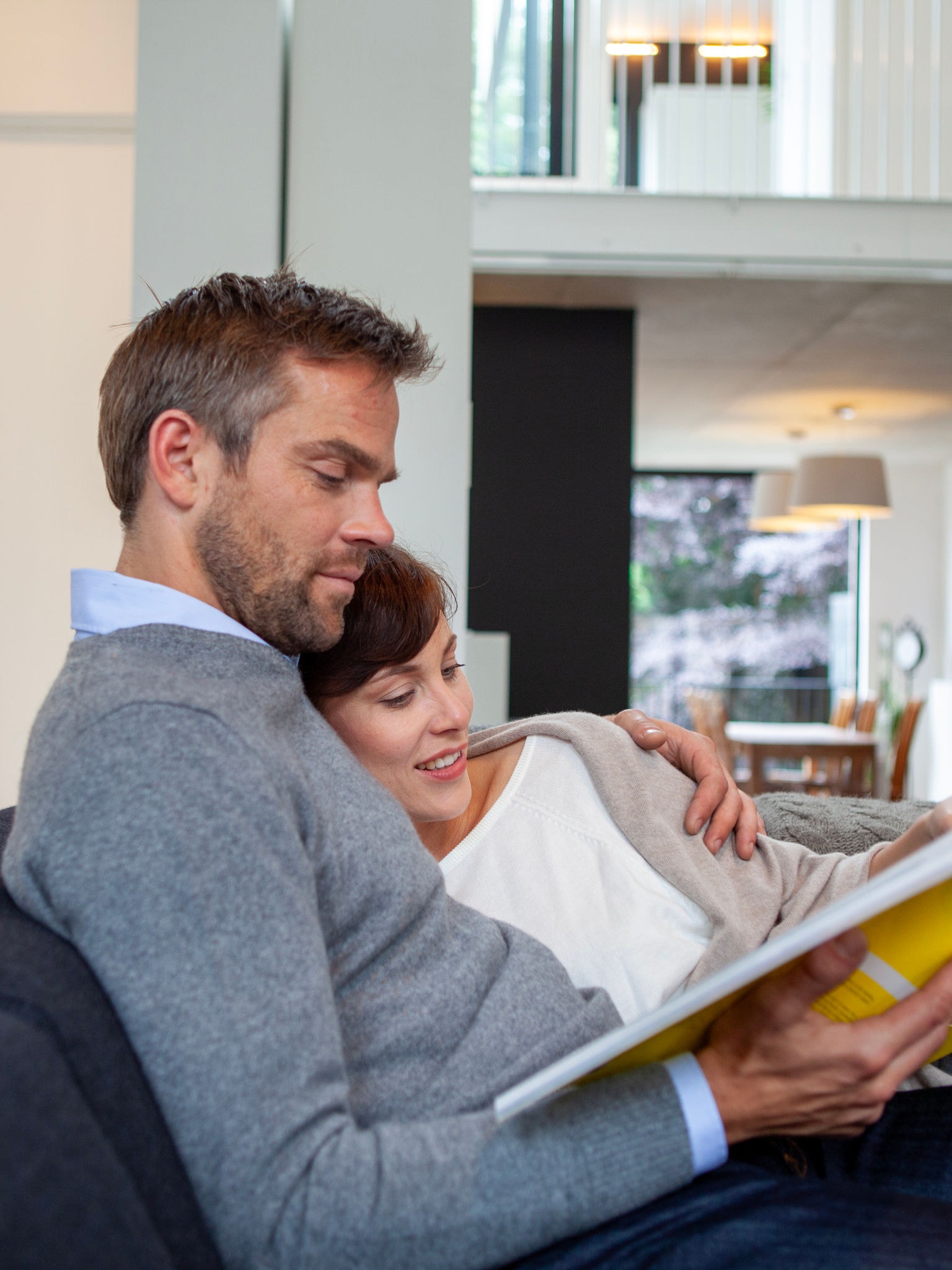 Ett par som myser och kopplar av på sin soffa medan de läser en bok i perfekt temperatur