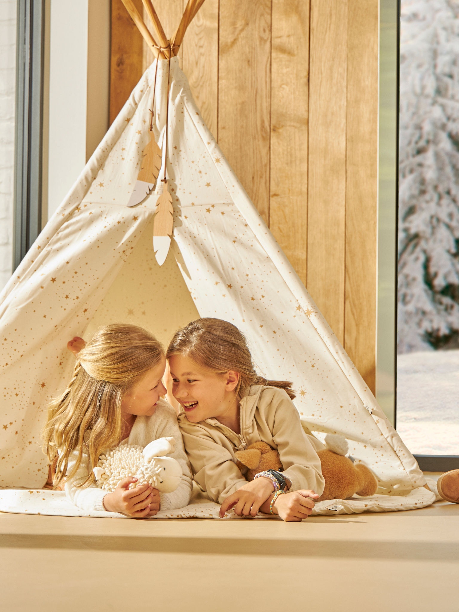 Två små barn som är glada och leker i sitt inomhustält i perfekt temperatur