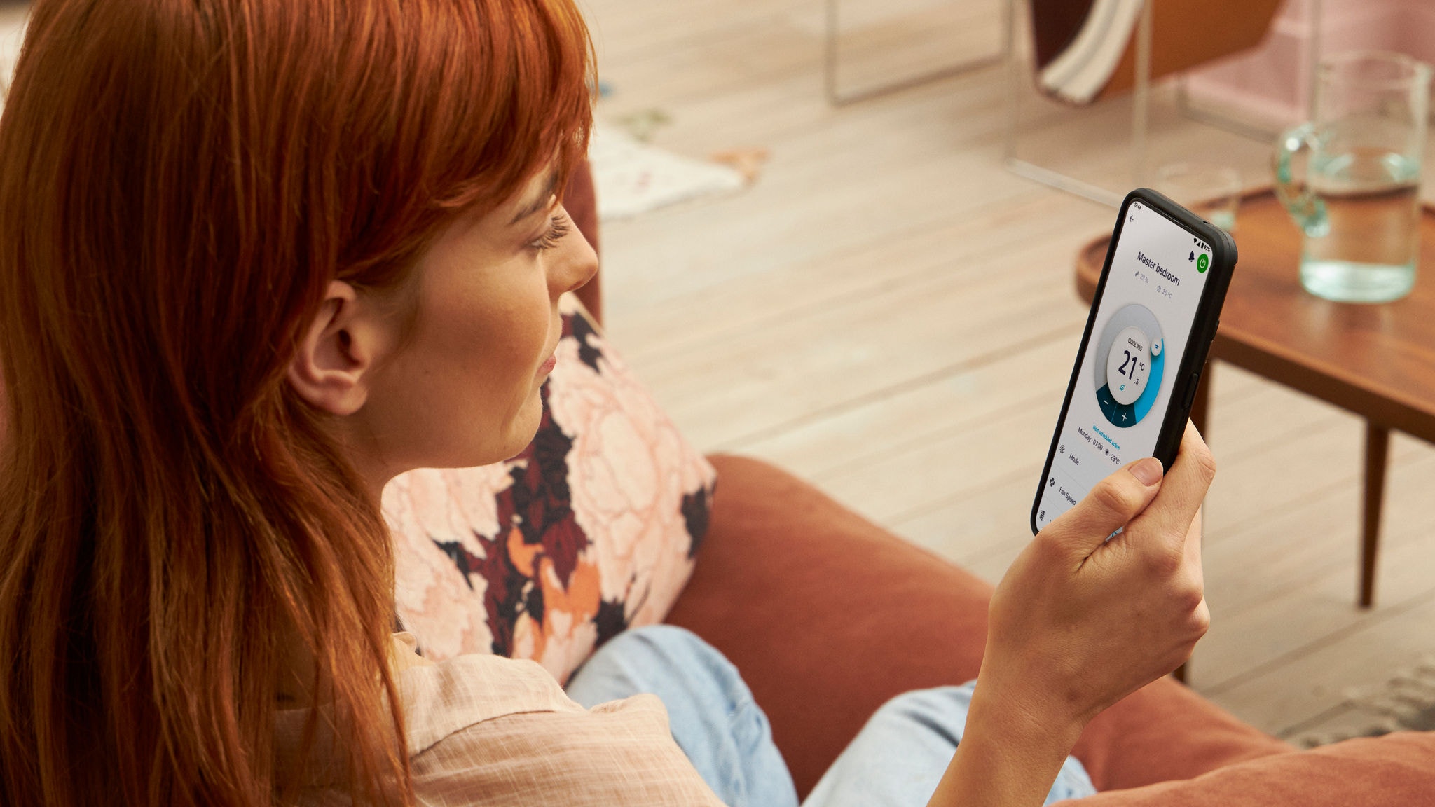En kvinna håller i en smartphone, och använder Onecta appen för att styra rumstemperaturen