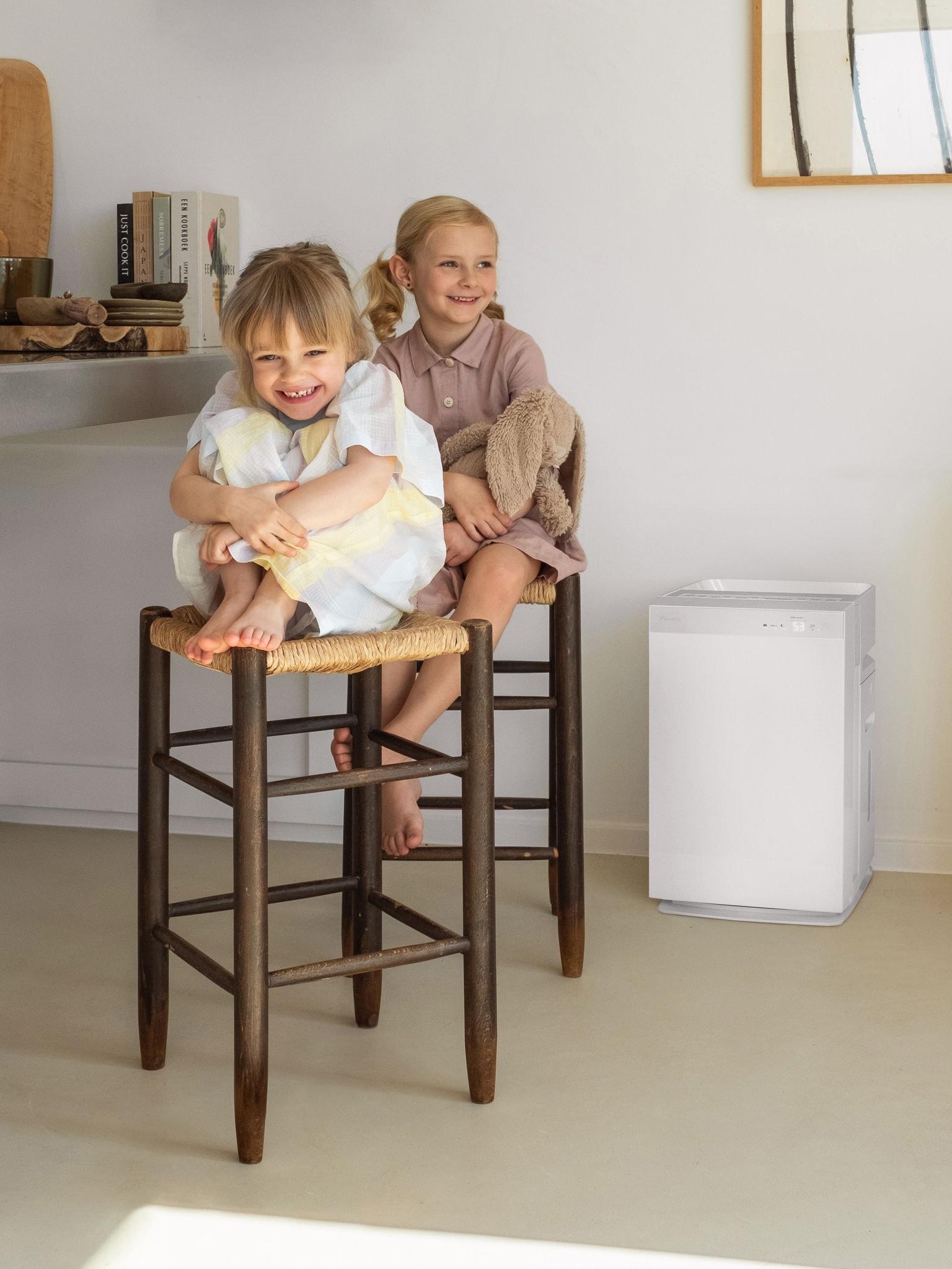 Two young sisters sitting on the kitchen stools and laughing