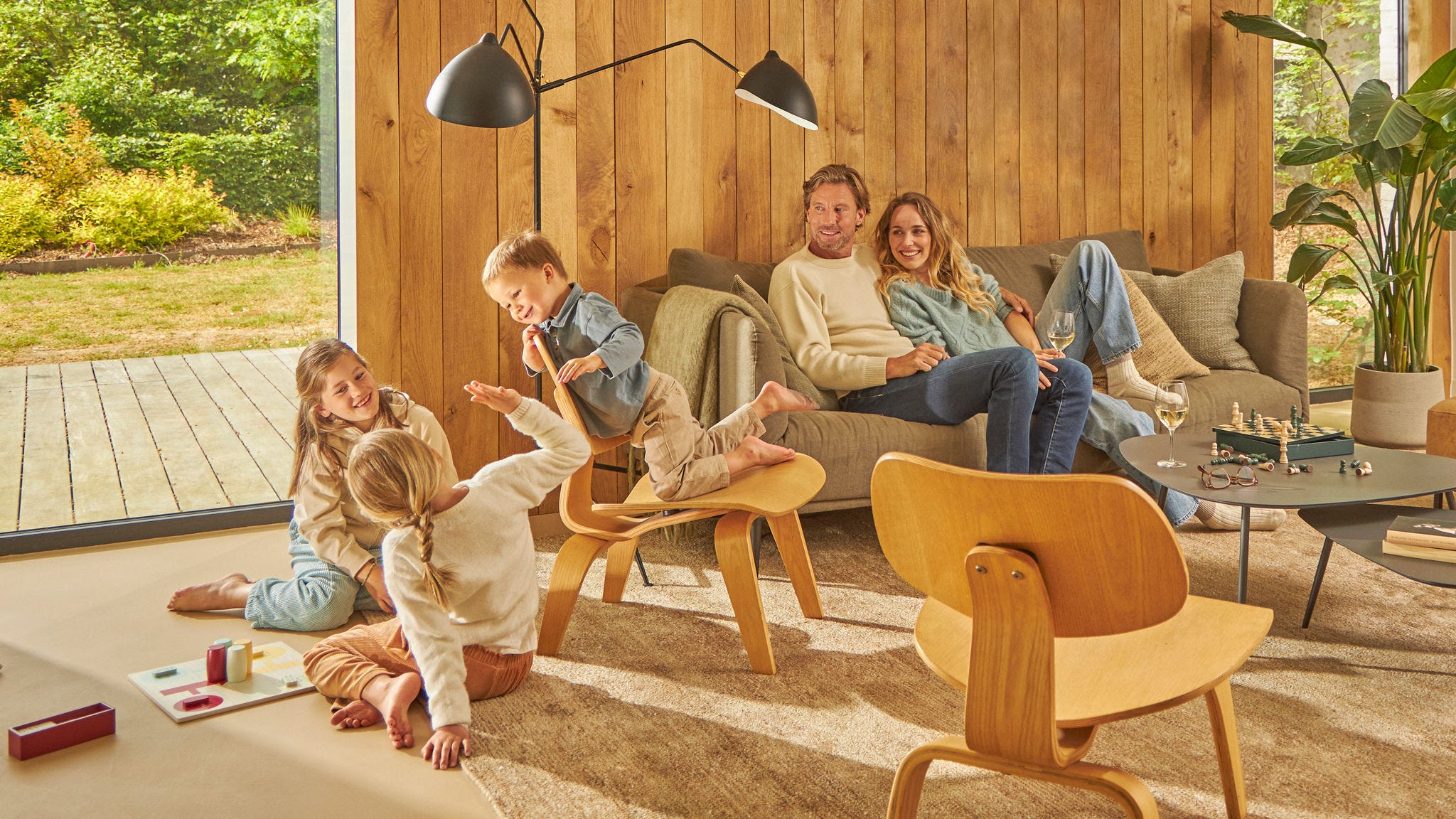 Familj med fyra personer som skrattar och spelar brädspel i sitt ventilerade kök