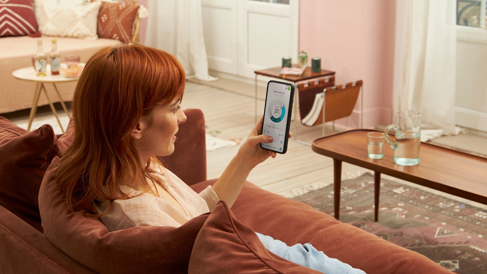 En man som sitter i soffan hemma och använder Onecta-appen på sin mobiltelefon