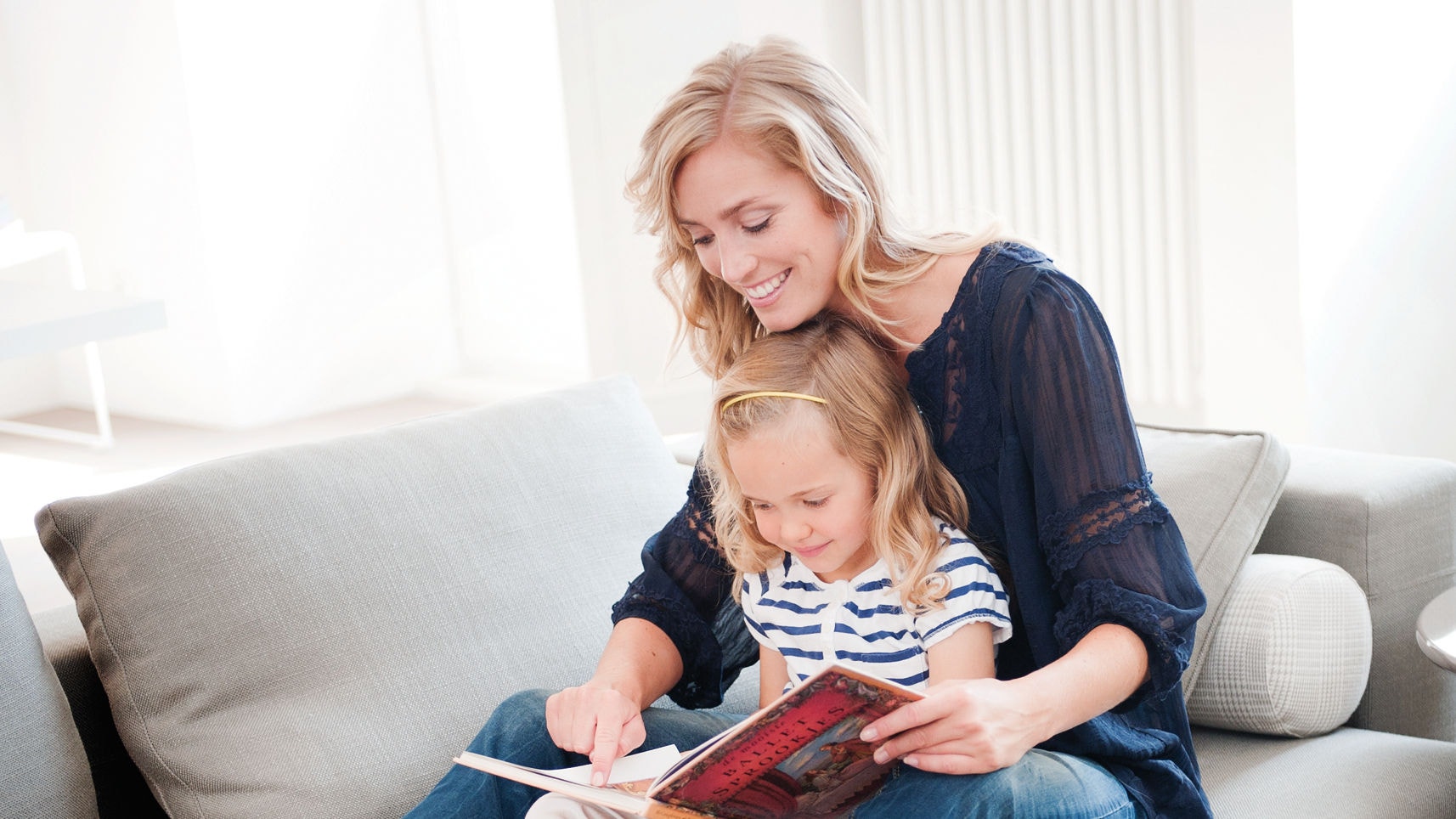 Mamma och dotter som läser en bok på soffan och njuter av perfekt inomhusklimat