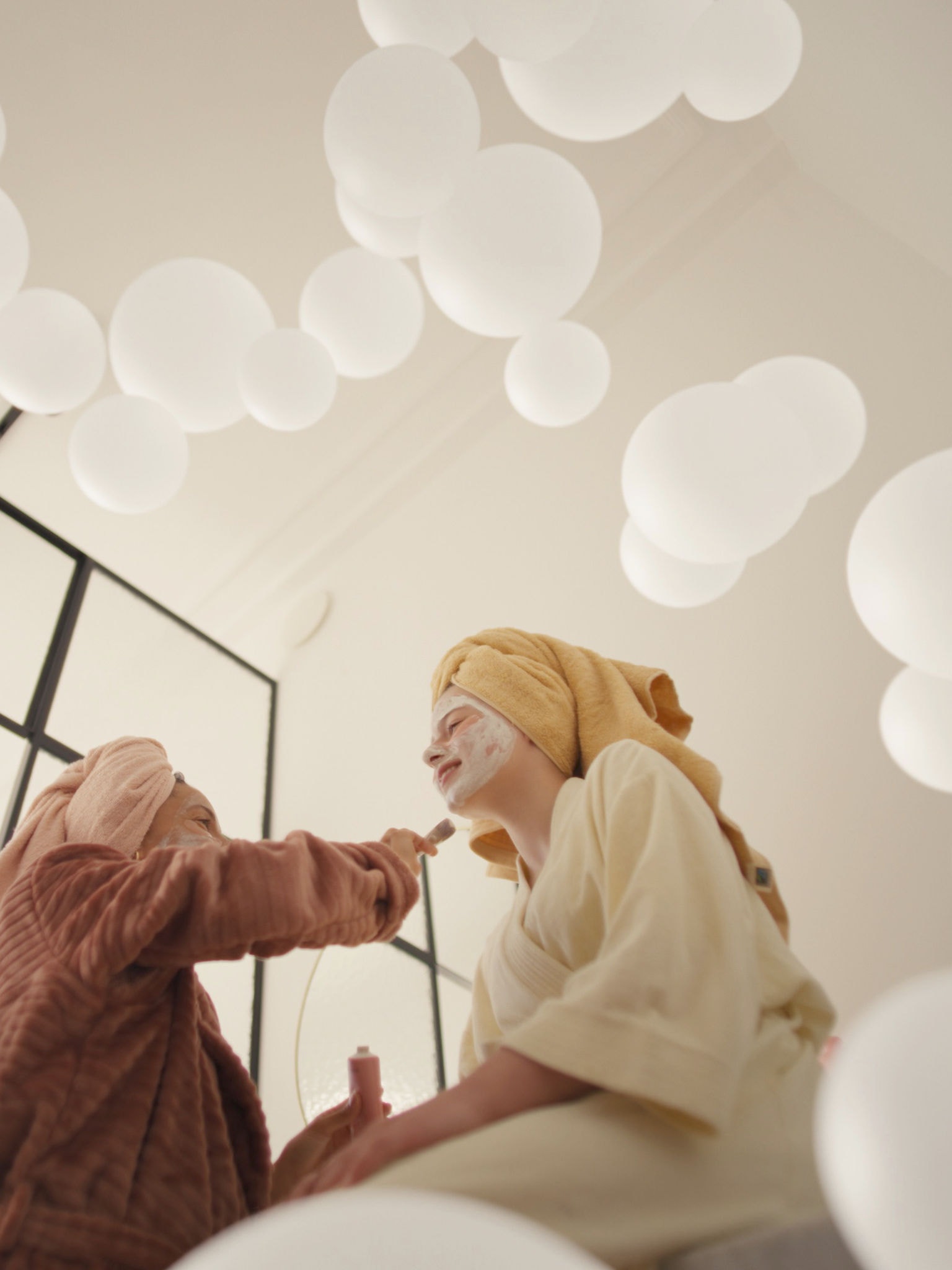 Mor och dotter njuter av egenvård med ansiktsmasker i ett välventilerat rum tack vare ett ventilationssystem med frisk luft