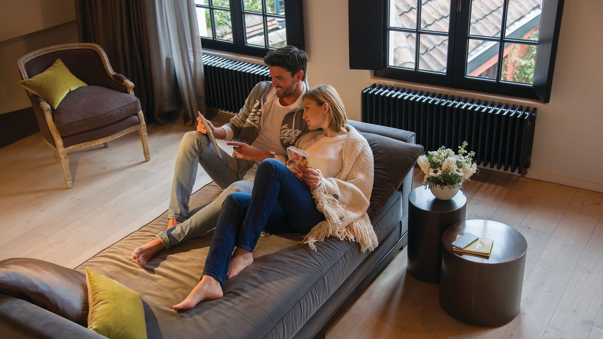 Par som kopplar av på en soffa och tittar på något på sin surfplatta