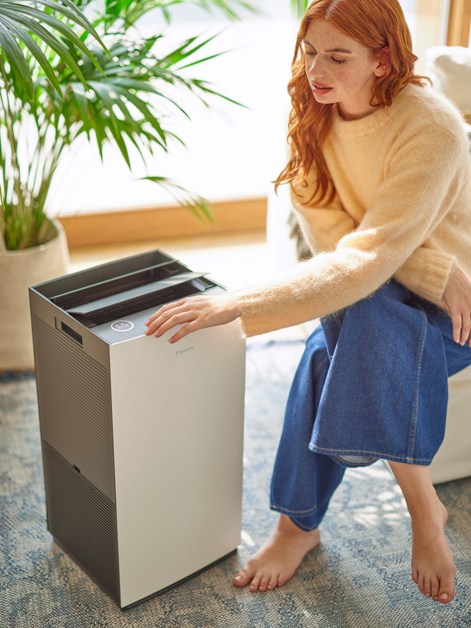 Kvinna i vardagsrummet som justerar inställningarna på en Daikin-luftrenare