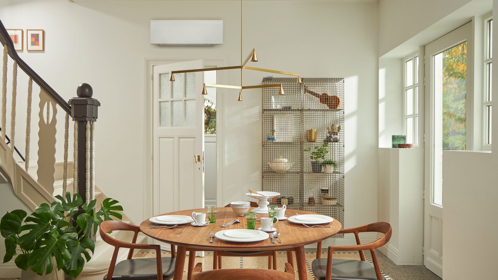 Rum med ett stort fönster, träbord och en svart väggmonterad klimatlösning