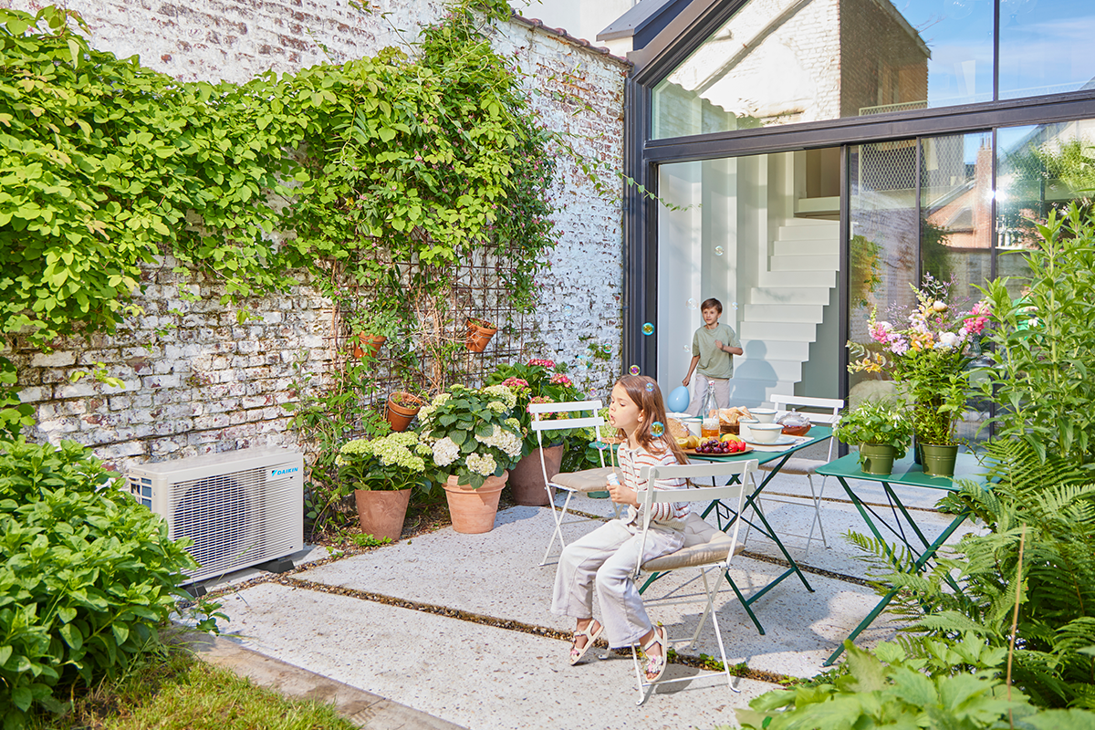 Barn som spelar kula på en trädgårdsterrass intill en utomhusplacerad värmepump