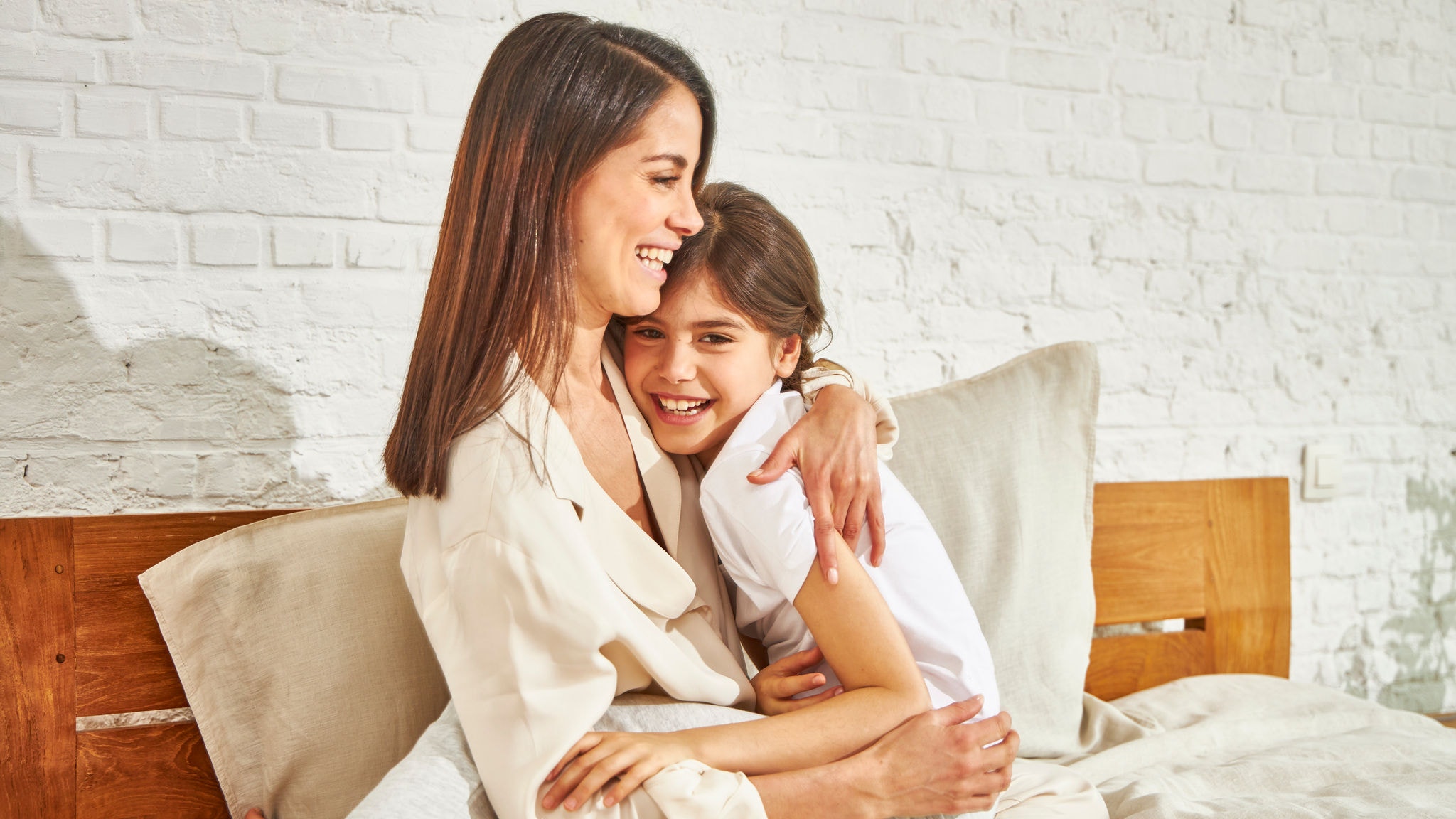 En mamma kramar sin dotter på sängen, och njuter av temperaturen
