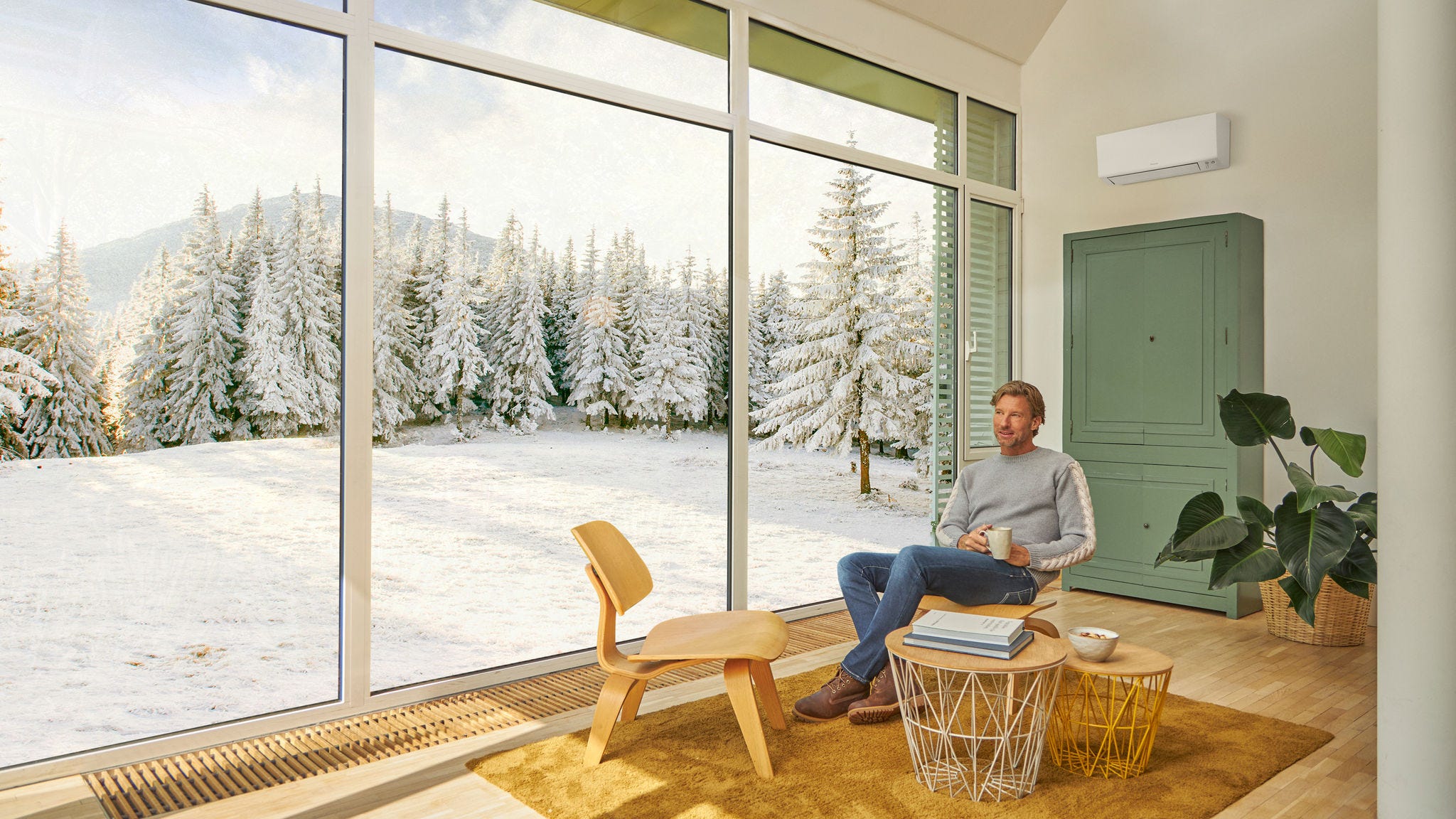 En man sitter i soffan och njuter av behaglig värme från en luftvärmepump