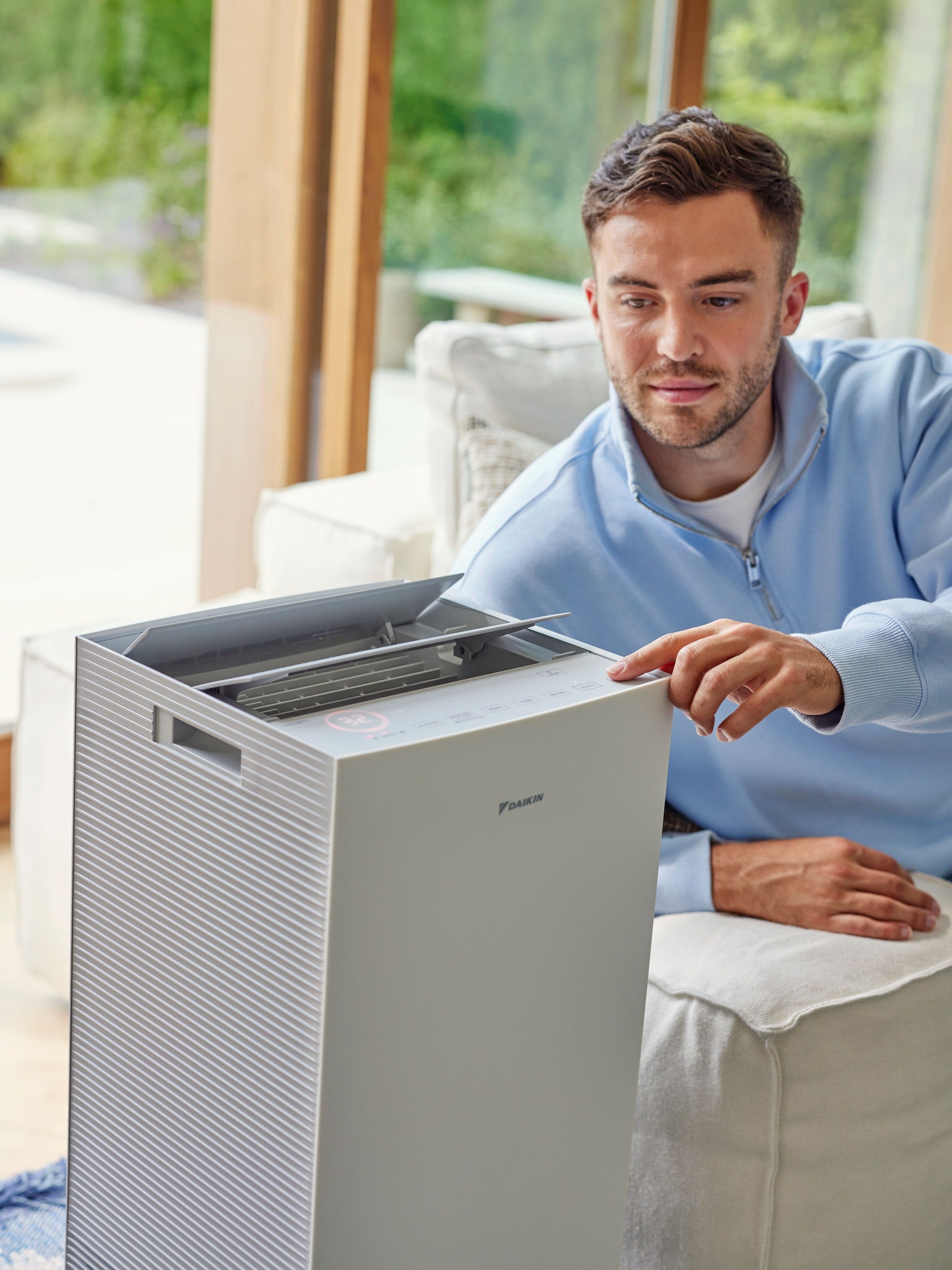 Man som justerar en Daikin-luftrenare i vardagsrummet för att minska kattallergener