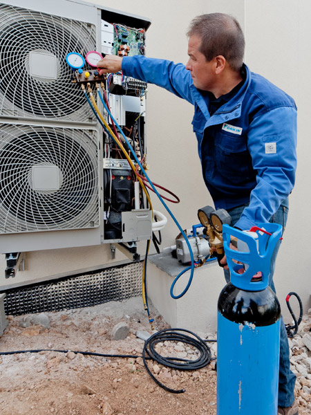 En Daikin servictekniker återvinner köldmedium från en luftvärmepump