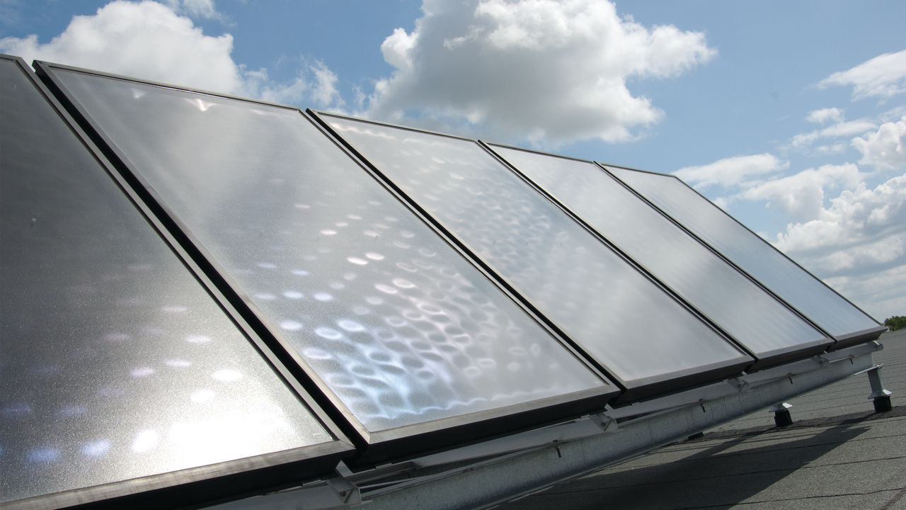 Solpaneler installerade på ett tak och anslutna till en värmepump från Daikin för att skapa synergi och spara pengar